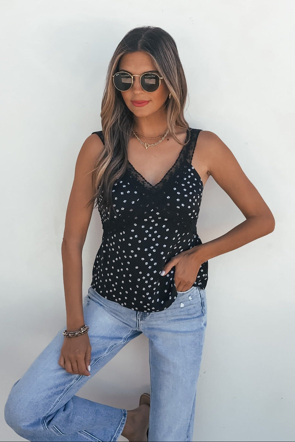 Woman wears sunglasses, the Midnight Lace Print Tank Top - Black, and light blue jeans against a plain white background.