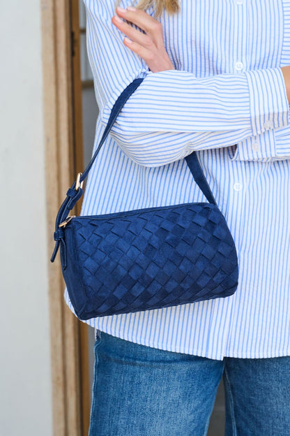 A person in blue stripes and jeans holds the Midnight Textured Vegan Leather Shoulder Bag with a strap.