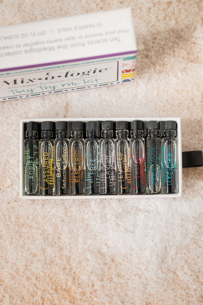 The Mixologie Tiny Try Me Perfume Kit has 10 alcohol-free vials, arranged in a white case on a textured surface.