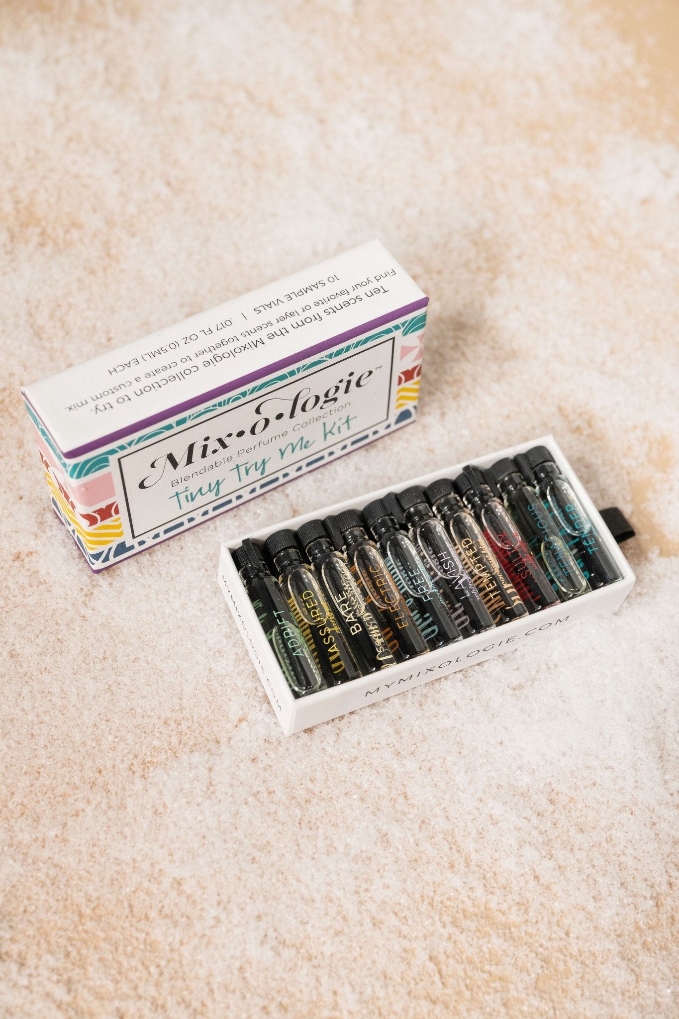 The Mixologie Tiny Try Me Perfume Kit includes nine alcohol-free vials in a white box on a light textured surface.