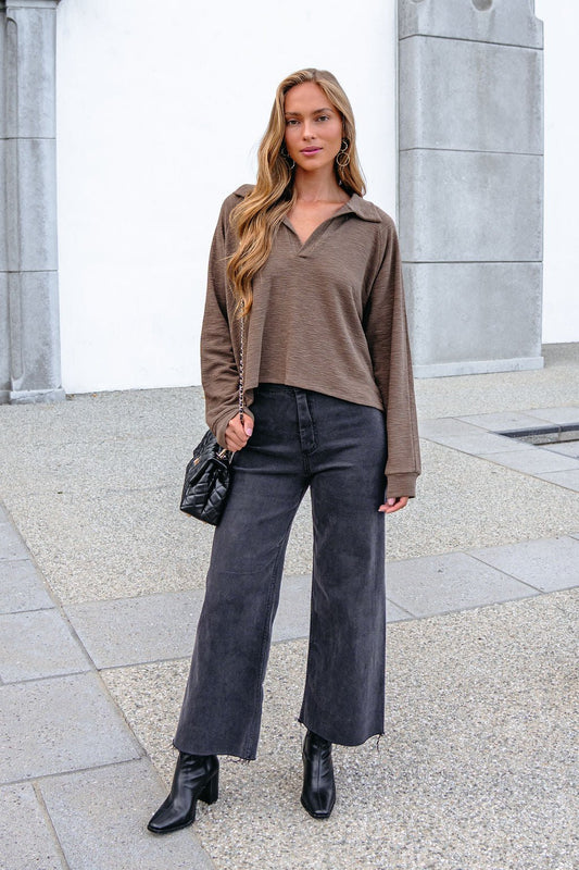 Woman in a Mocha Collared High Low Pullover, black wide-leg jeans, and boots stands on a city sidewalk with an oversized fit.