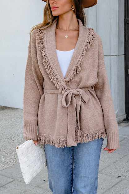 Woman in Mocha Fringe Tie Cardigan | Pre Order, white top, jeans, brown hat, holding a white clutch outside.