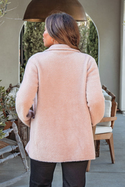 A woman with long brown hair wears a Mocha Fuzzy Open Front Coatigan and black pants, standing outdoors with her back to the camera.
