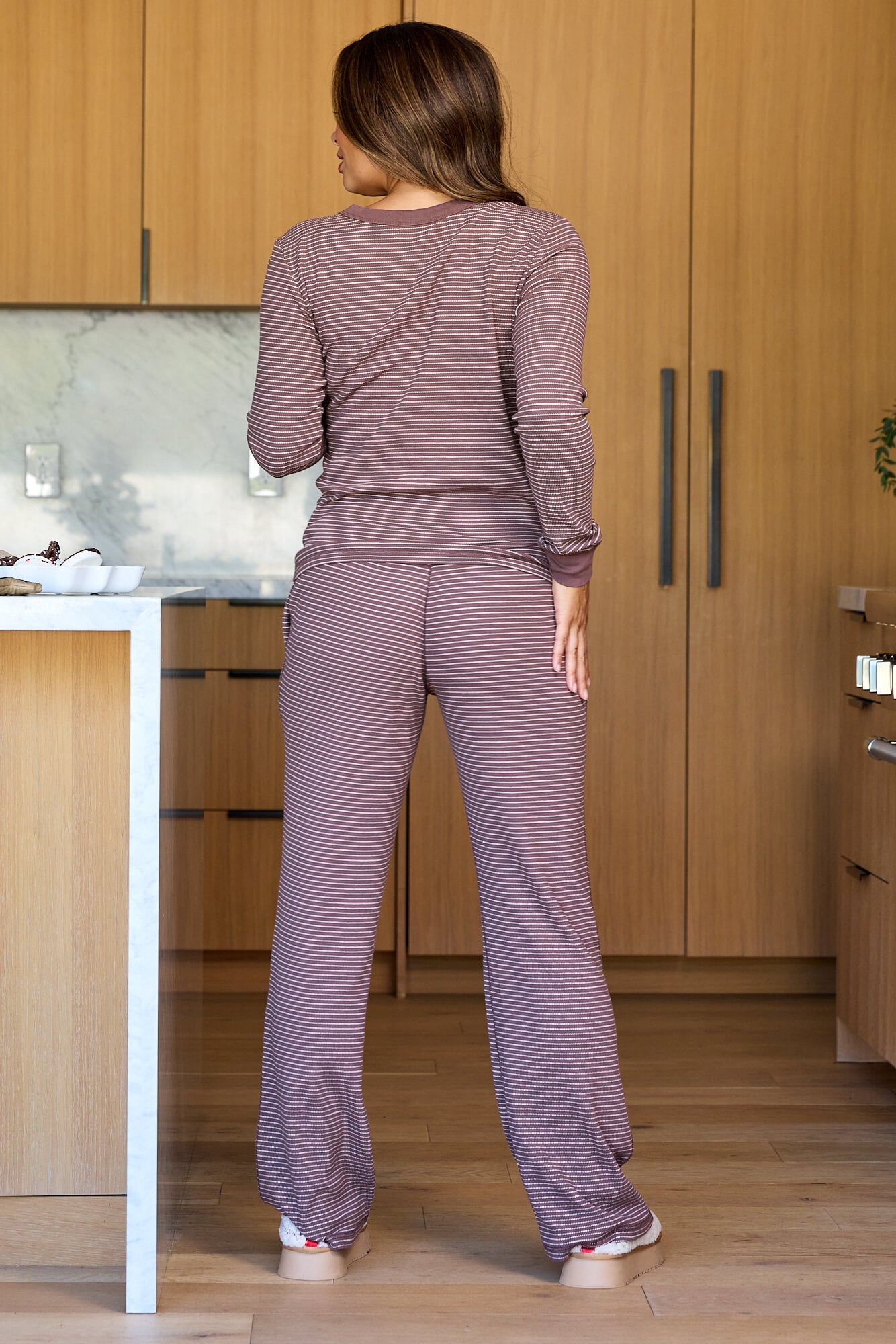 A woman in a Mocha Striped Long Sleeve Thermal Top stands in a modern kitchen, facing away from the camera.