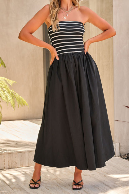 Woman in the Monaco Strapless Midi Dress - Black, featuring bold contrast stripes on the bodice, standing outdoors.