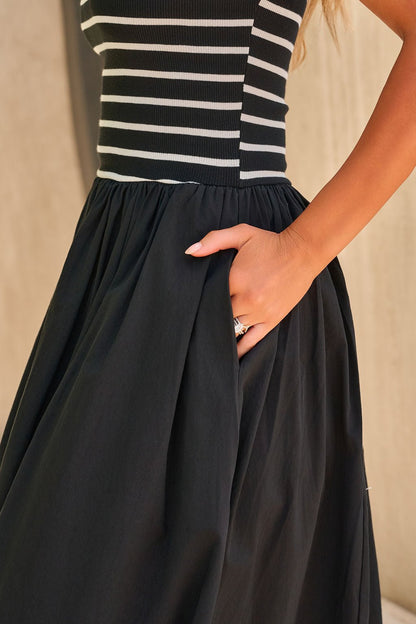 Woman wearing the Monaco Strapless Midi Dress in black, her hand casually tucked in the dress pocket.