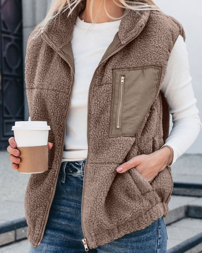 Woman in a Mountainside Zip Up Fleece Vest - Mocha and white long-sleeve holds coffee, showcasing a cozy fall look outdoors.