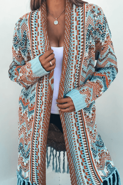 Woman wearing a Multi Aztec Stripe Boho Fringe Cardigan over a white top with gold jewelry, standing against a plain background.