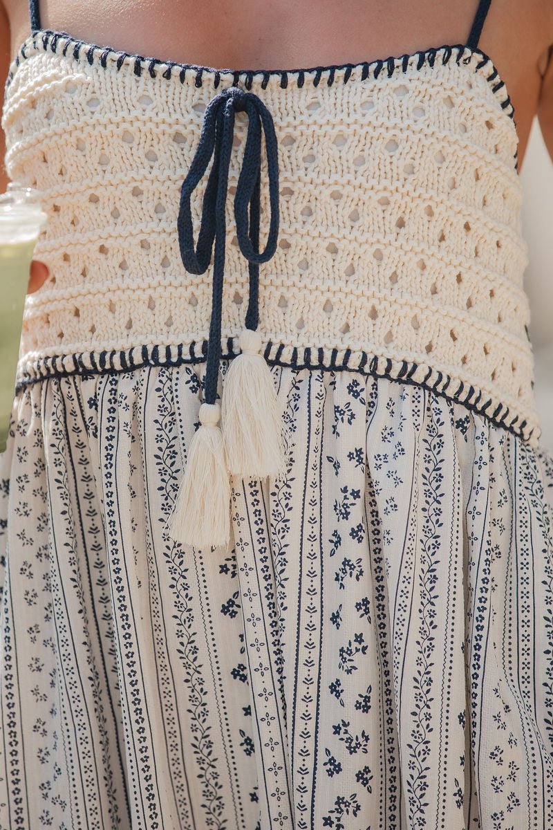 Close-up of the Multi Navy Stripe Crochet Maxi Dress with tassel ties and a patterned skirt featuring blue florals.