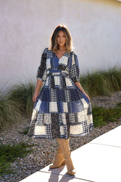 Woman in the Multi Navy Patch Print Midi Dress stands outside on a sunny day near grass and rocks.