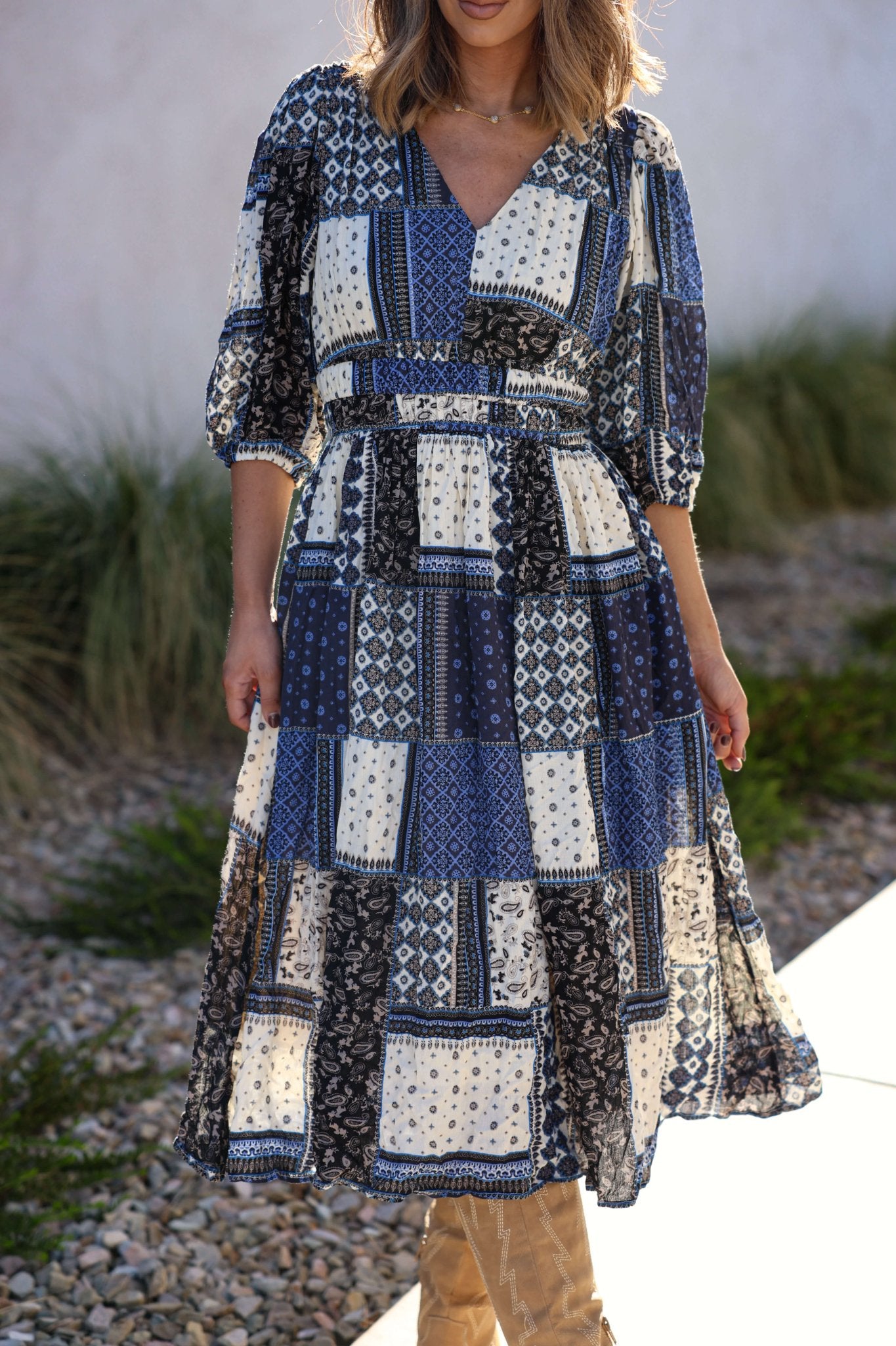 Woman wearing the Multi Navy Patch Print Midi Dress - FINAL SALE with puff sleeves, standing outdoors on a sunny day.