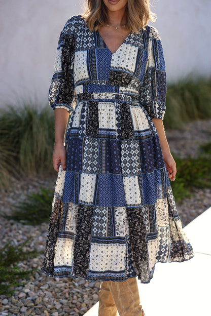 Woman wearing the Multi Navy Patch Print Midi Dress - FINAL SALE with puff sleeves, standing outdoors on a sunny day.