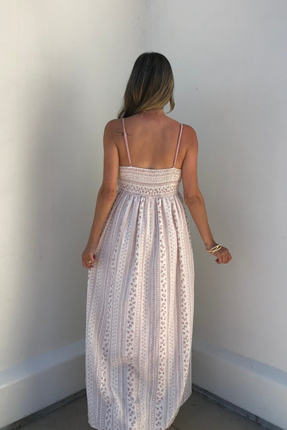 A woman with long hair stands with her back to the camera in a Multi Pink Stripe Crochet Maxi Dress against a white wall.