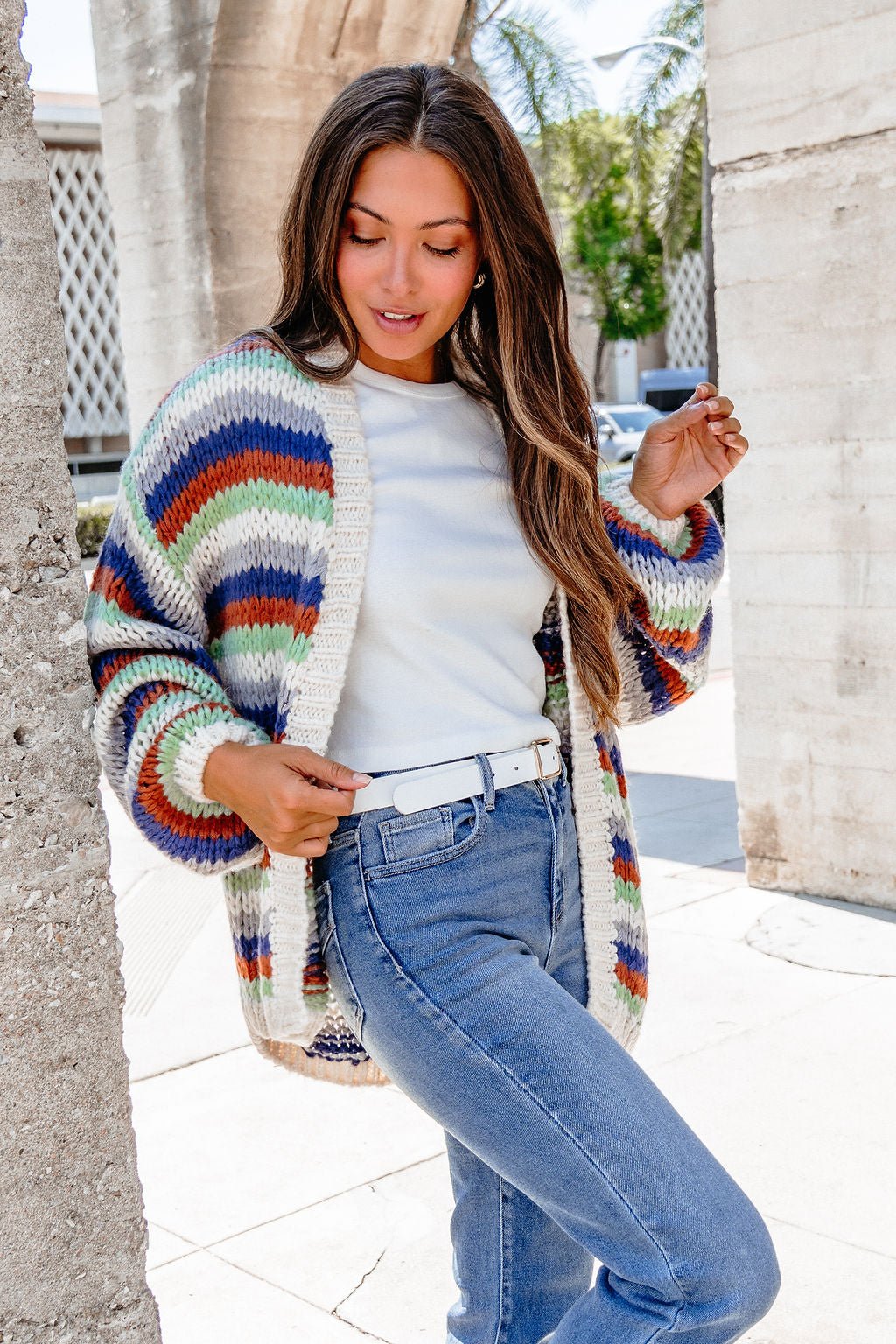 A woman layers the Multi Striped Open Front Sweater Cardigan—FINAL SALE—over a white shirt and jeans for a chic fall look.