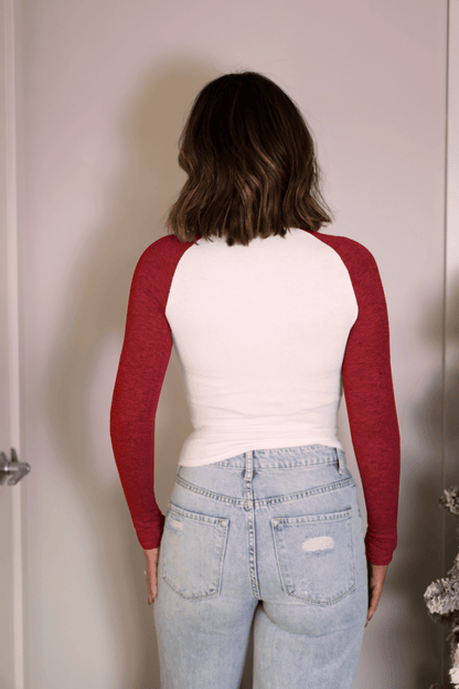A person with shoulder-length brown hair wears the Natalie Red Color Block Tee and light blue jeans, standing with back to camera.