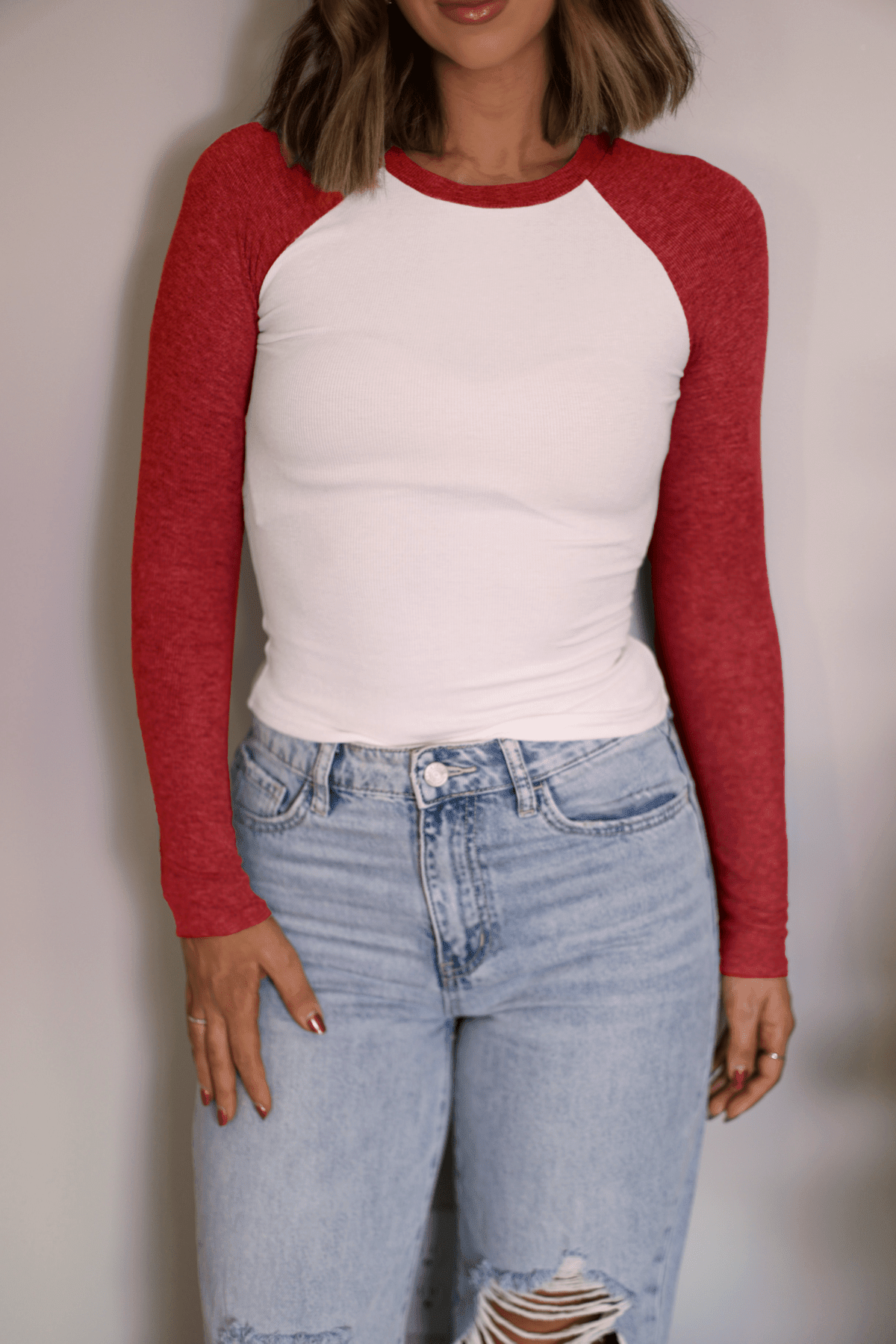 Woman wears the Natalie Red Color Block Tee with light blue ripped jeans—a versatile, casual look on a plain background.