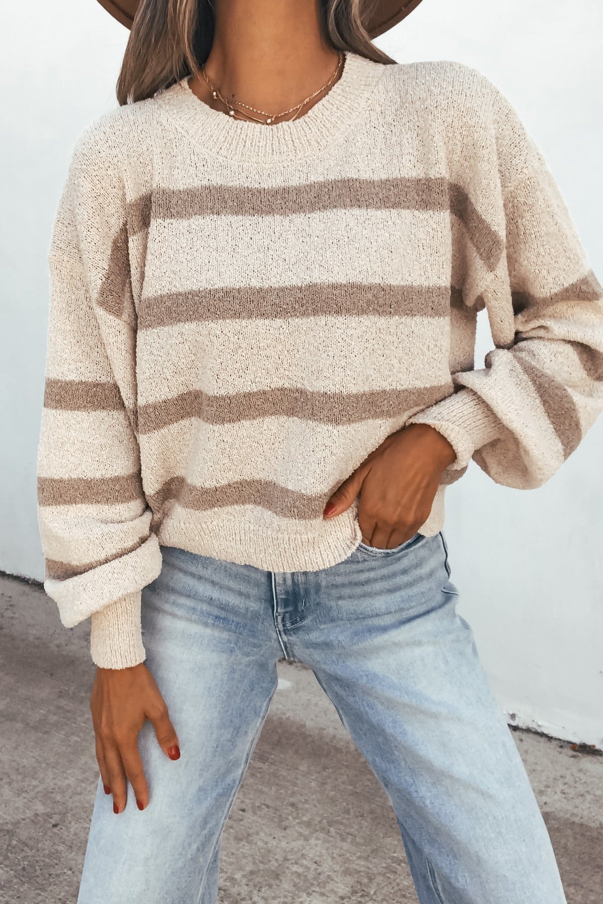 A fall staple: the Natural & Mocha Striped Sweater pairs with light blue jeans for a cozy, effortless outdoor look.