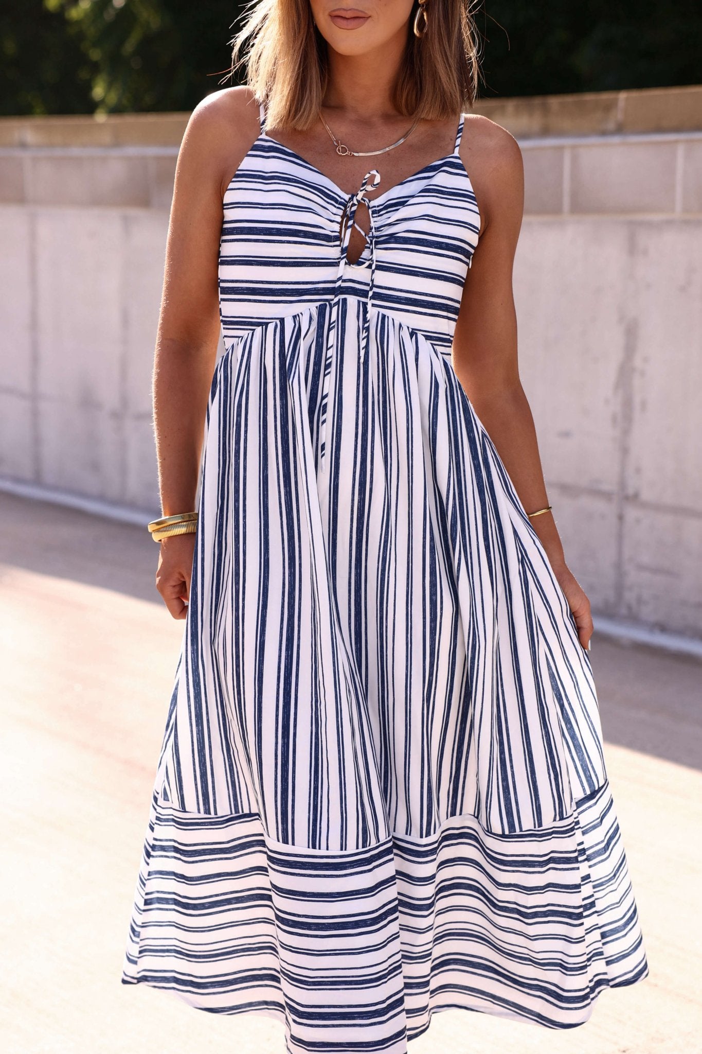 Woman in a Navy and White Striped Tie Front Midi Dress, perfect for summer, standing outdoors in sunlight.