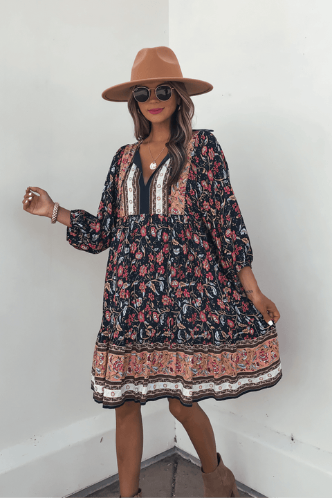 Woman in a Navy Floral Border Print Mini Dress - FINAL SALE, styled with a tan hat and sunglasses for effortless fall fashion.