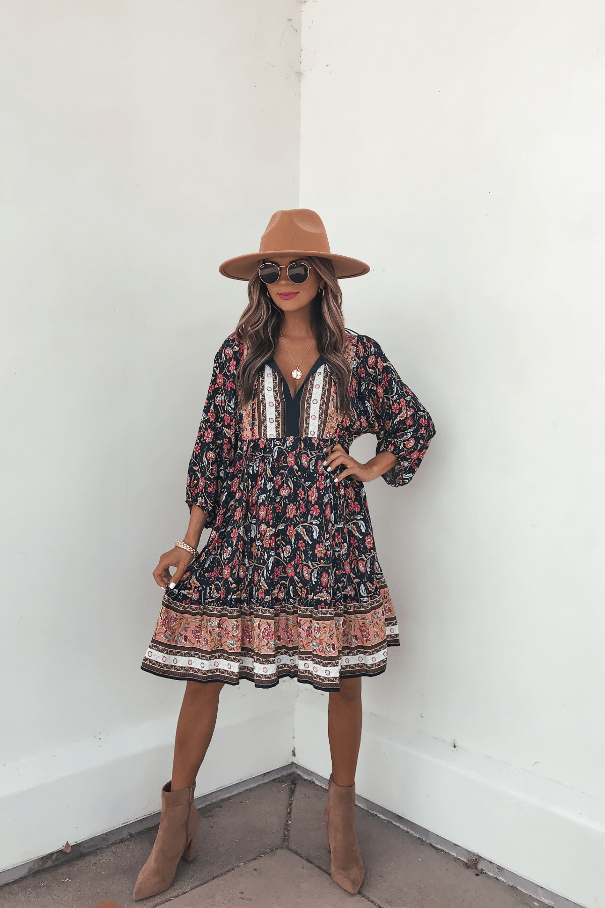 Woman in the Navy Floral Border Print Mini Dress - FINAL SALE, paired with a tan hat and boots—perfect for your fall wardrobe.