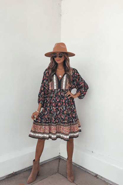 Woman in the Navy Floral Border Print Mini Dress - FINAL SALE, paired with a tan hat and boots—perfect for your fall wardrobe.