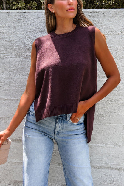Woman in a Nine To Five Cashmere Sweater - Mocha and light blue jeans, standing by a white textured wall.