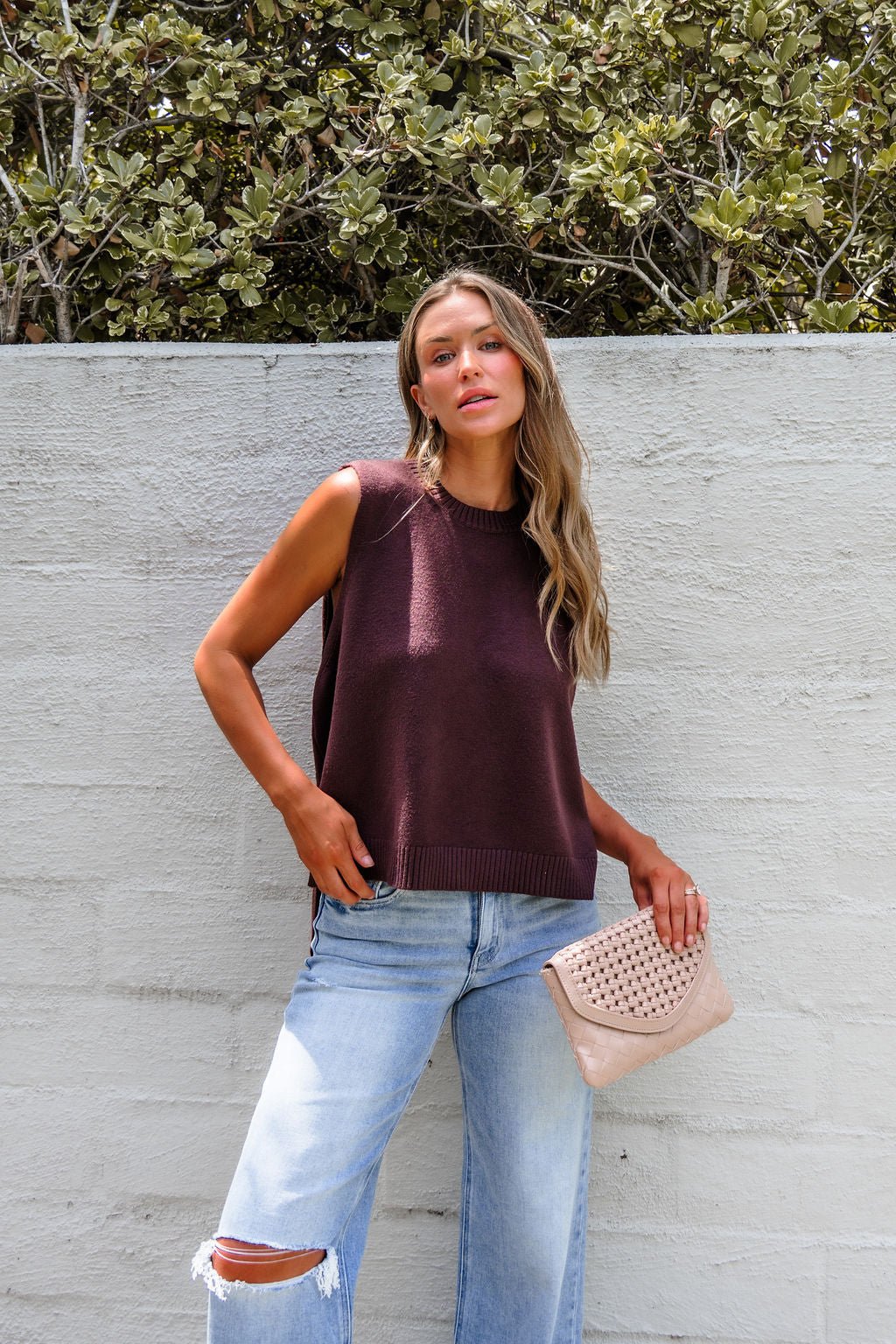 Woman in the Nine To Five Cashmere Sweater - Mocha styles it effortlessly with ripped jeans and a beige clutch for a chic look.