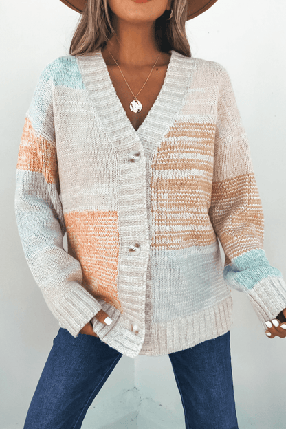 Woman in an Oatmeal Color Block Button Down Cardigan, blue jeans, hat, and necklace against a plain background.