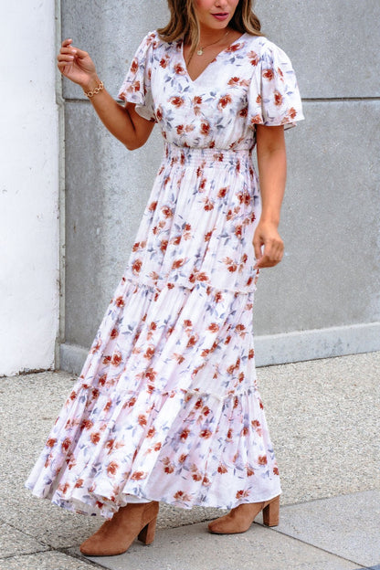 Woman in an Oatmeal Floral Print Smock Tiered Maxi Dress, standing outdoors in tan heeled boots.
