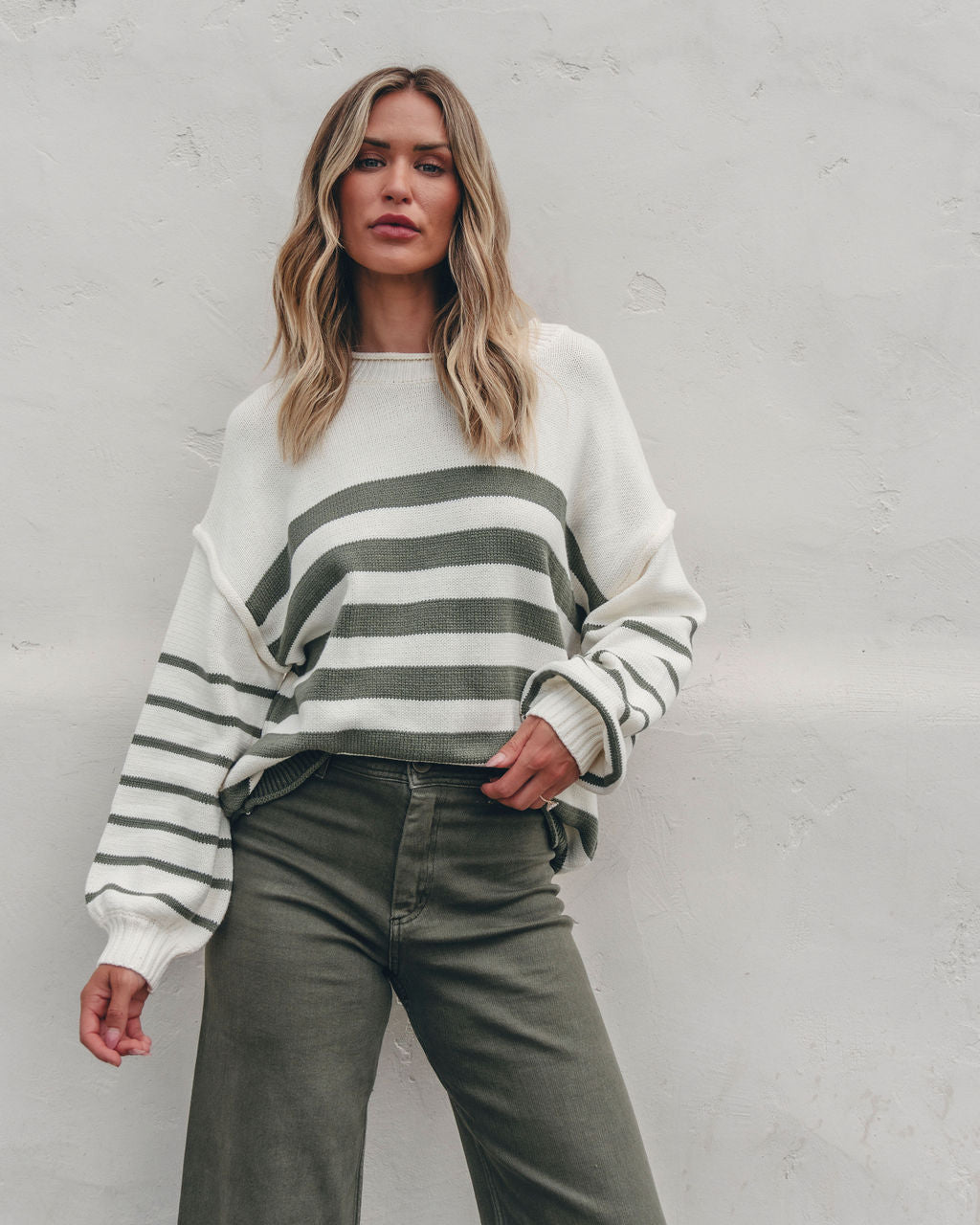Woman in an Olive and Cream Striped Pullover Sweater with olive pants—perfect fall outfit inspiration.
