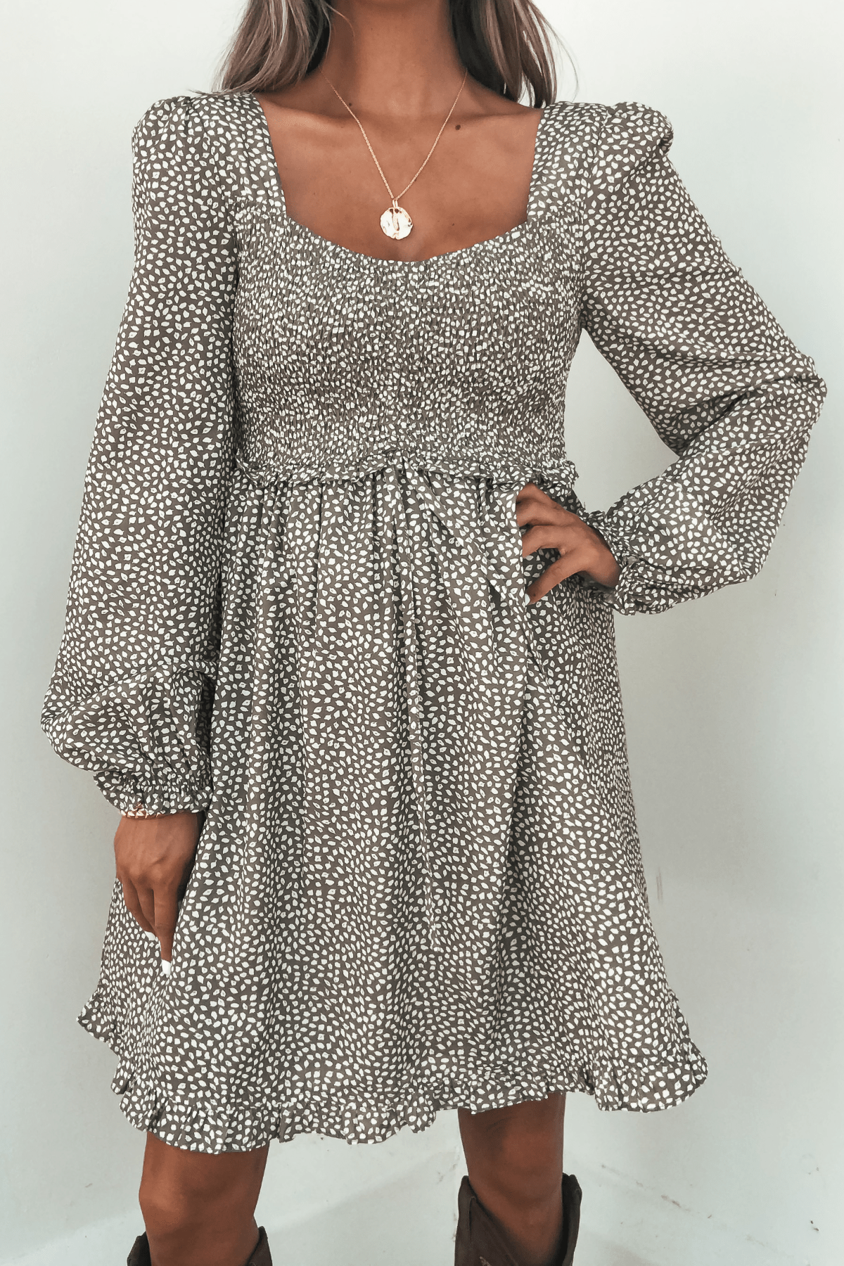 Woman wearing the Olive Floral Print Ruched Mini Dress, featuring long sleeves and a square neckline, against a plain background.