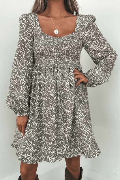Woman wearing the Olive Floral Print Ruched Mini Dress, featuring long sleeves and a square neckline, against a plain background.