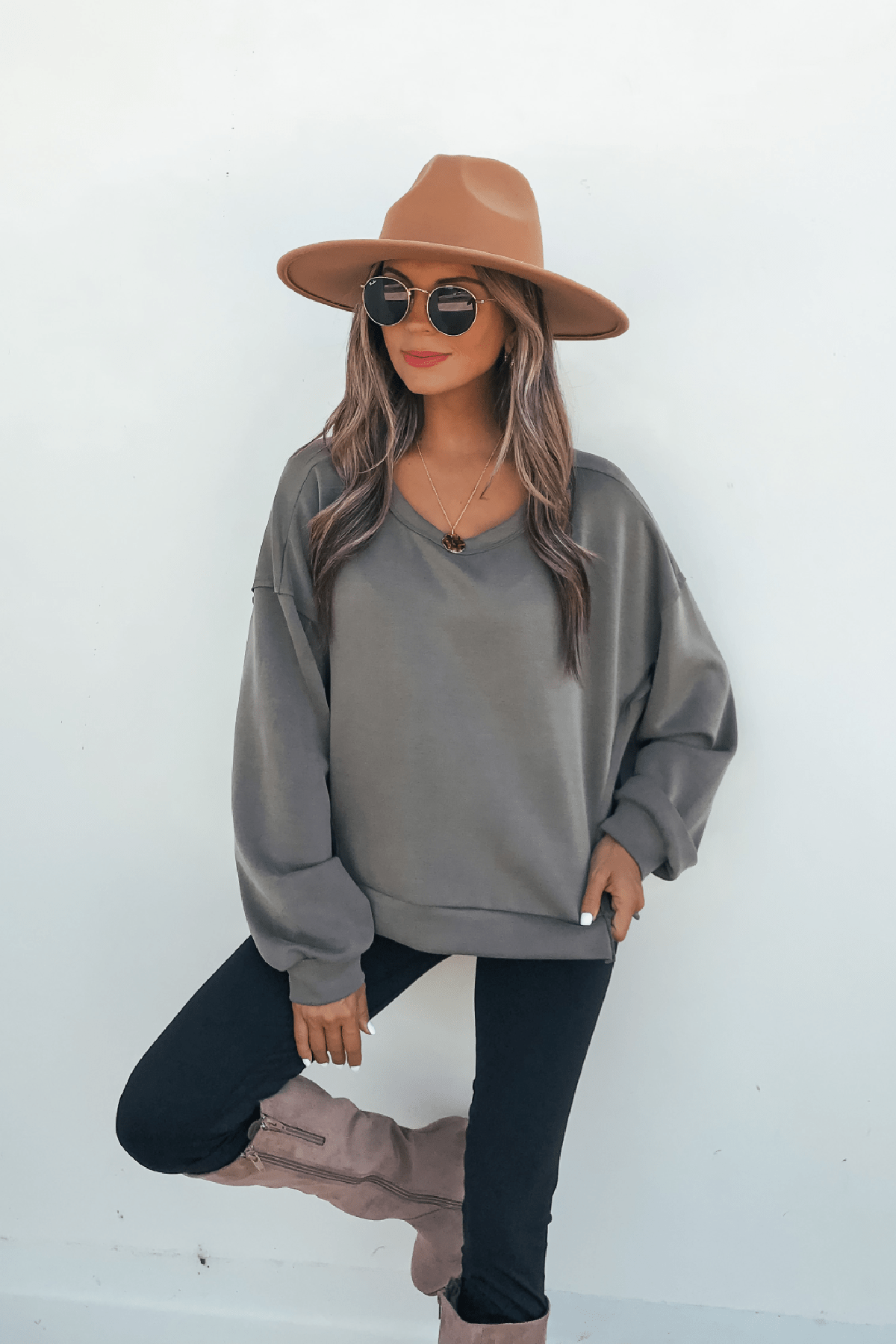 Woman in sunglasses and a tan hat wears the Olive Soft Cloud Scuba Top, black pants, and tan boots against a white background.