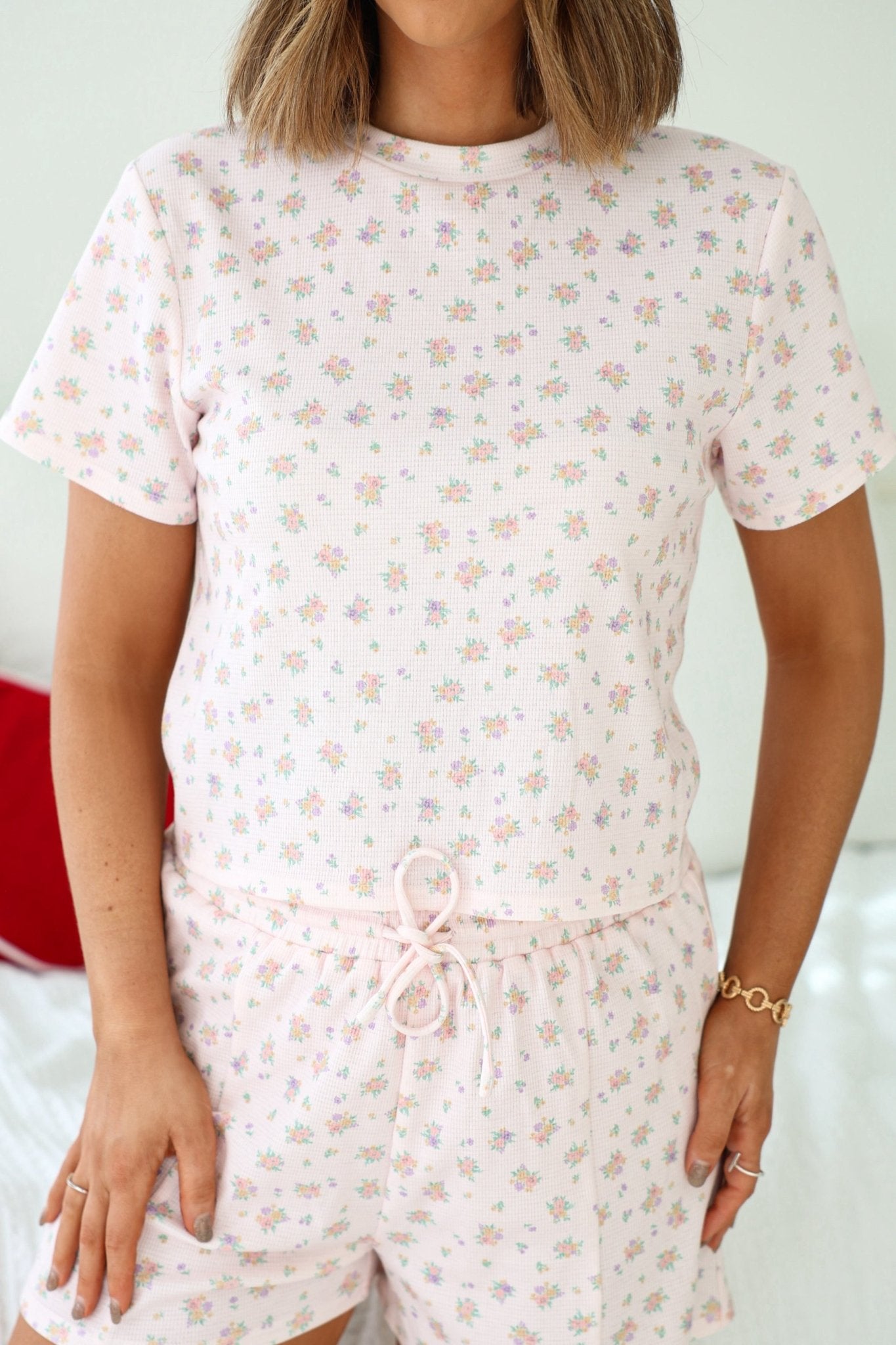 Woman wearing the Pink Floral Print Lounge Set with short sleeves, featuring a small floral print, standing indoors.