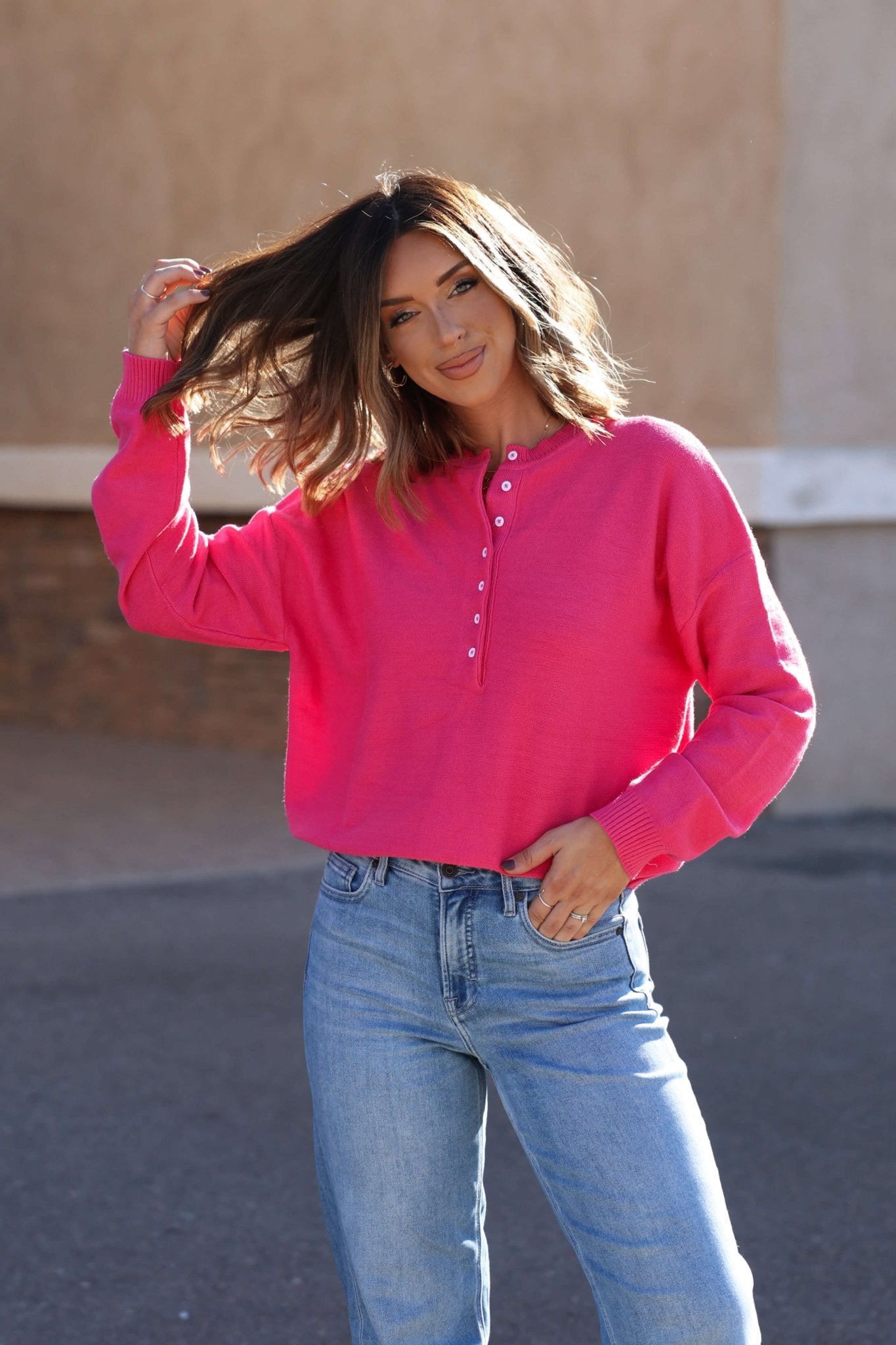 Smiling woman in a Pink Henley Button Up Sweater and blue jeans—your must-have fall essential.