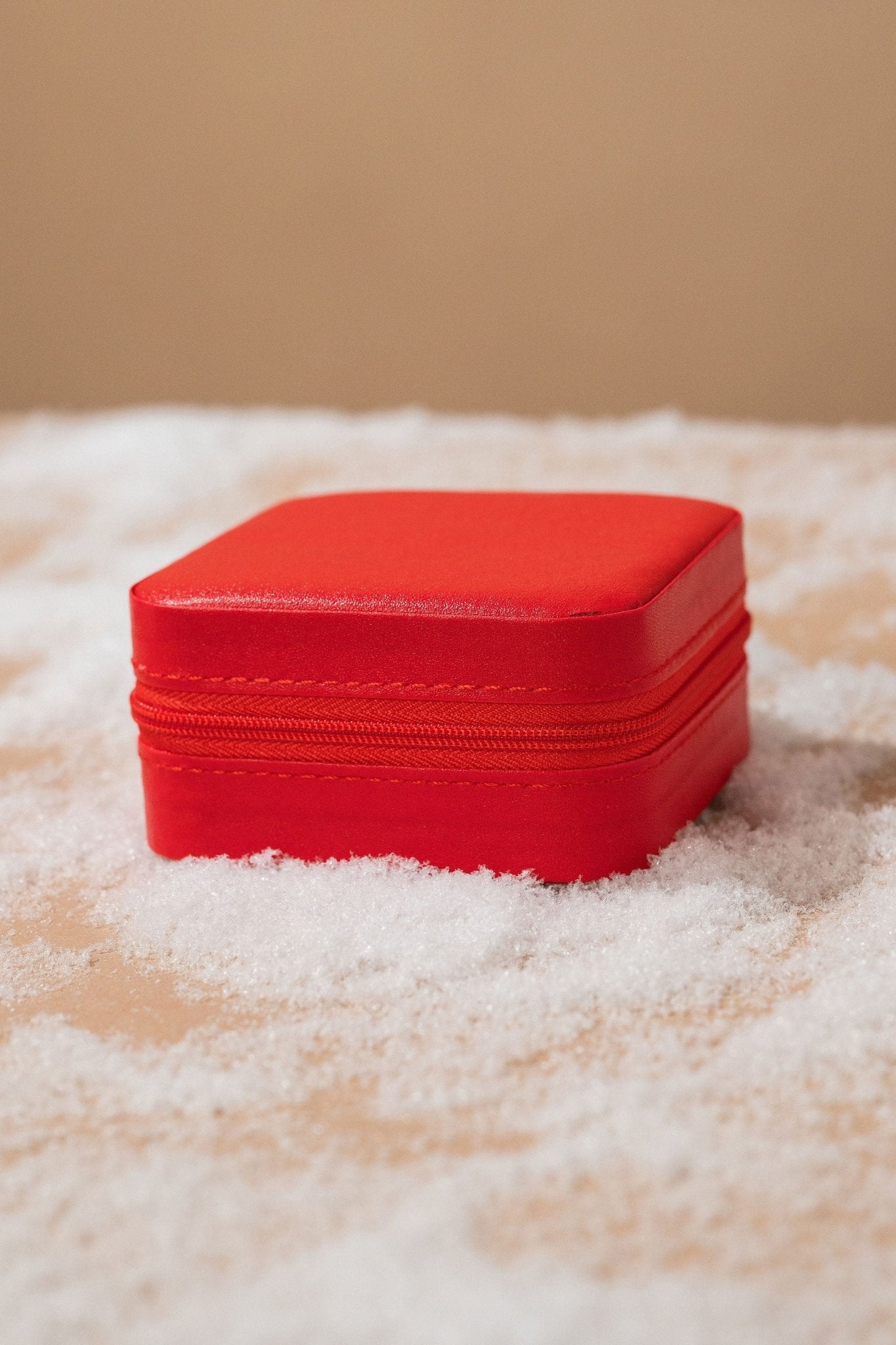 The Portable Red Leather Jewelry Box is shown closed on snow with a beige background.