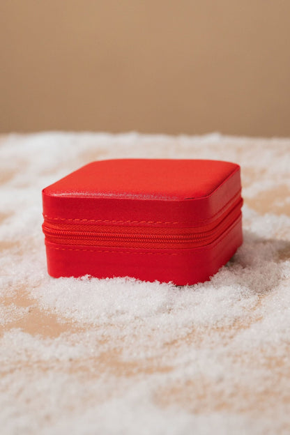 The Portable Red Leather Jewelry Box is shown closed on snow with a beige background.