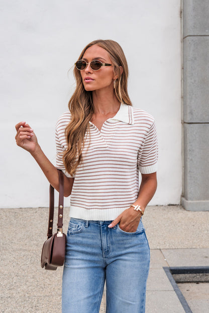 Woman in sunglasses wears the Adair Striped Sweater - Dark Taupe, blue jeans, and a brown purse near a white wall.