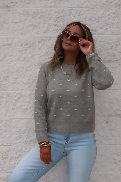 A woman in the Ramona Sage Polka Dot Ribbed Sweater and light jeans poses, accessorized with sunglasses and layered necklaces.