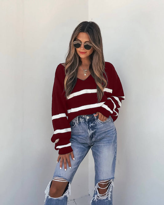Model wears a Red and White Striped V Neck Sweater with ripped jeans and sunglasses for a chic fall look.