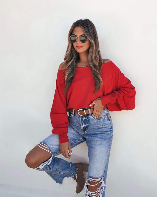 A woman wearing a Red Boatneck Cashmere Sweater and distressed blue jeans.