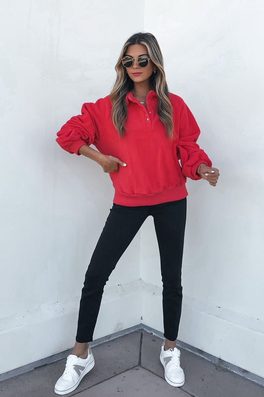 A person wearing a cozy Red Button Up Fleece Pullover, black pants, and white sneakers.