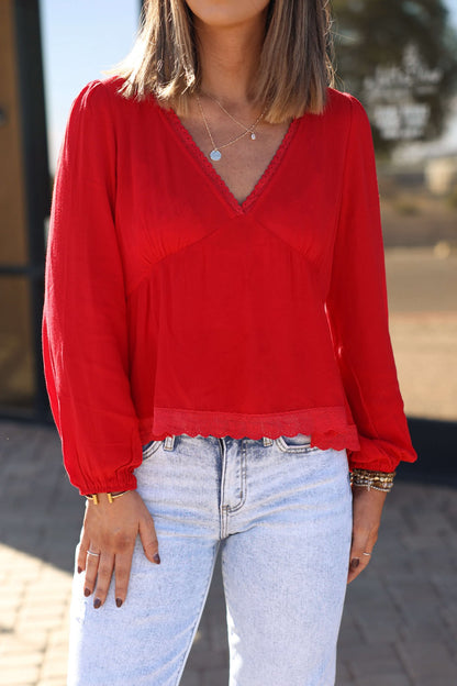 Woman in a Red Lace Trim Babydoll Top - FINAL SALE and light blue jeans, posing outdoors for a feminine fall look. Face not visible.
