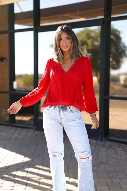 Woman in a Red Lace Trim Babydoll Top - FINAL SALE and ripped jeans, enjoying a sunny day in a chic fall look.