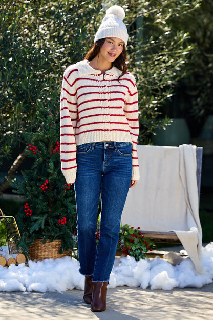 Woman wears the Red Striped Button Down Knit Cardigan - FINAL SALE with jeans and boots outdoors near faux snow and greenery.