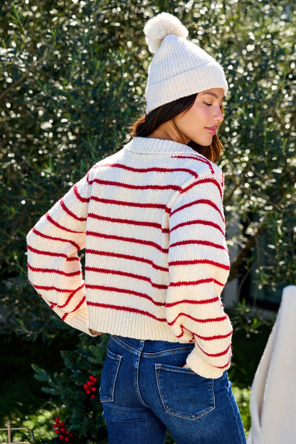 A woman outdoors wears the Red Striped Button Down Knit Cardigan - FINAL SALE, facing away and looking over her shoulder.
