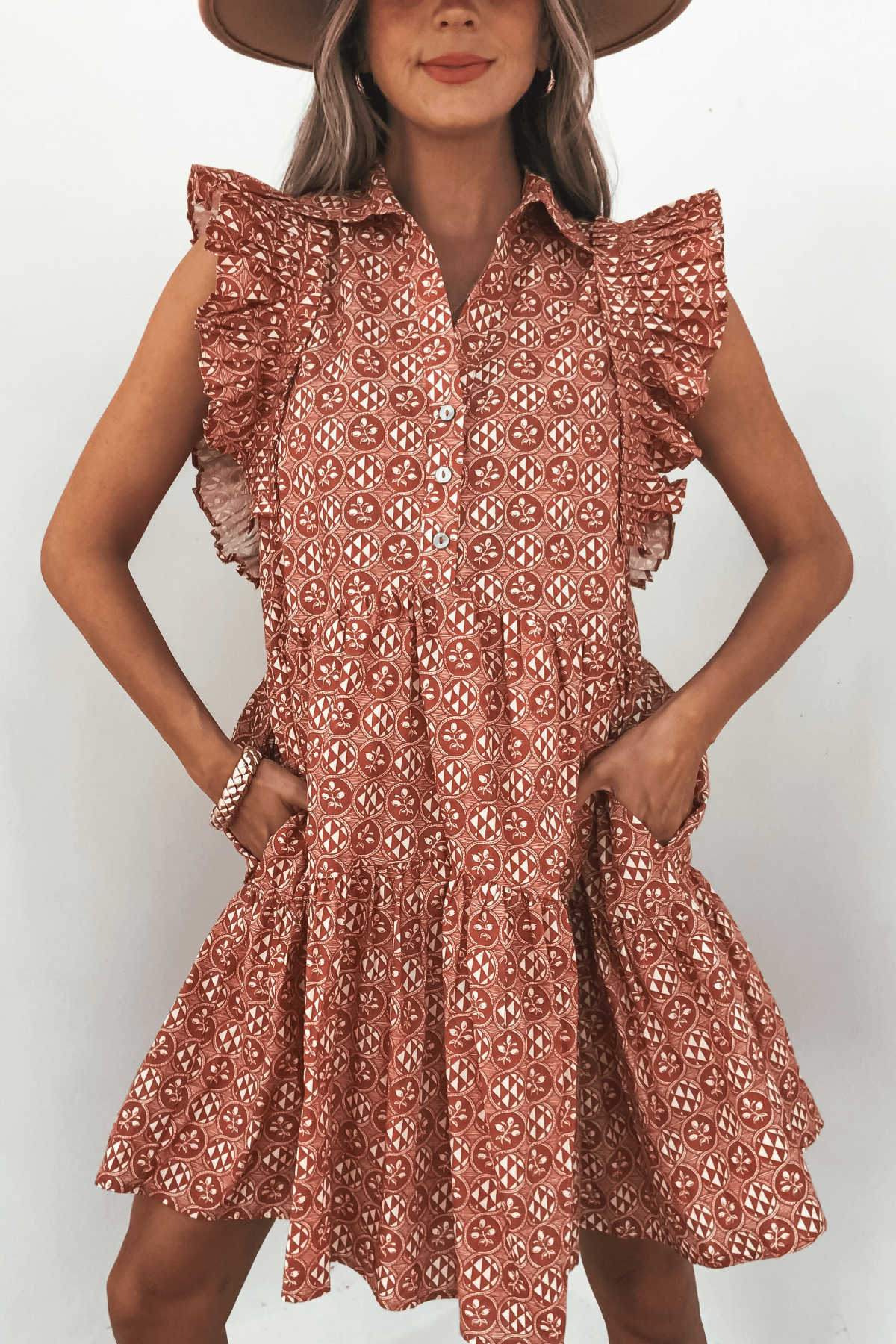 Woman wearing the Rust Print Flutter Sleeve Mini Dress - FINAL SALE, hands in pockets, against a white background.