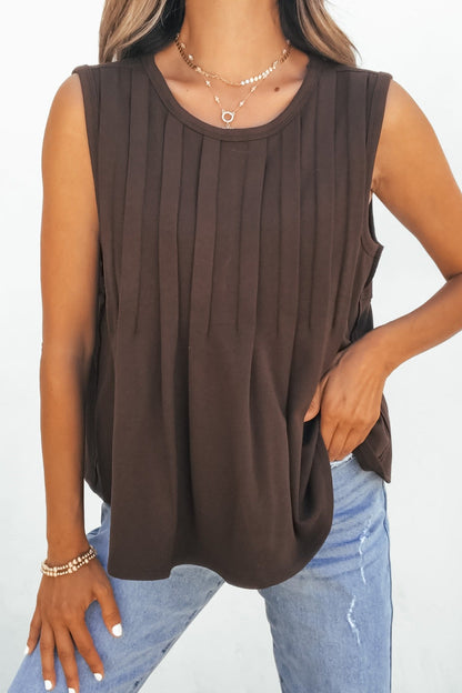 Woman in Sable Pleated Top - Brown, layered necklaces, bracelets, and light blue jeans with a hand in her pocket.