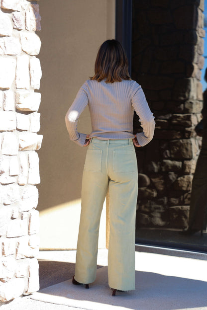 A woman stands outside with her back to the camera, wearing Sage Straight Wide Leg Pants and a beige top for a chic casual look.