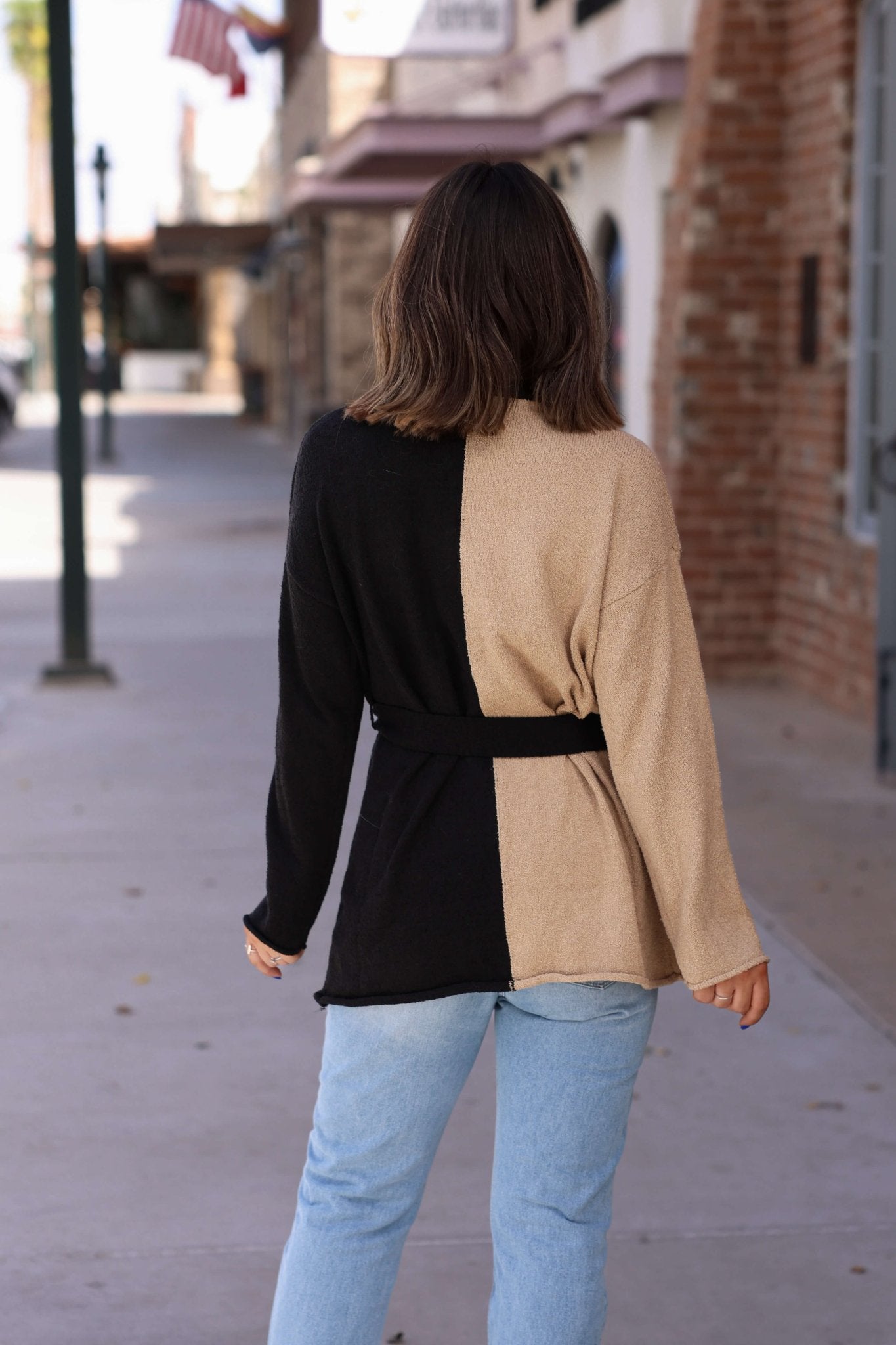 A woman in the Sand Color Block Button Down Cardigan - FINAL SALE and light blue jeans, perfect for fall layering.